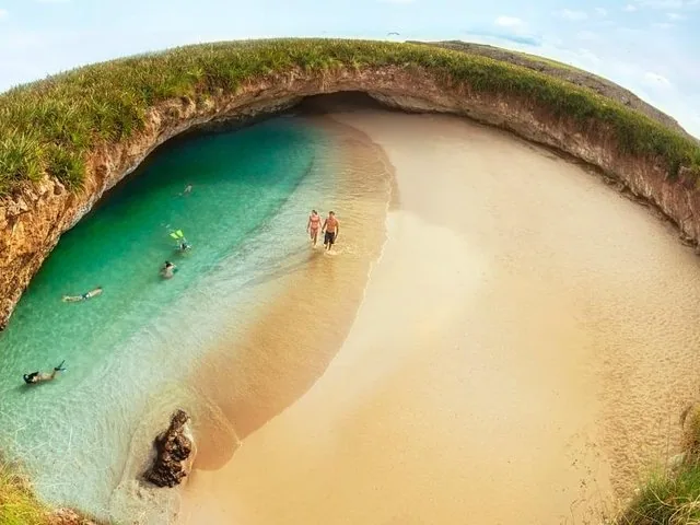Menschen, die am Sandstrand von Hidden Beach entlanggehen